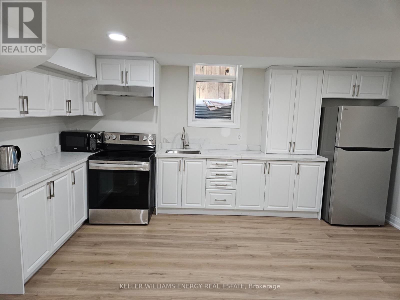 A kitchen with white cabinets and a stainless steel refrigerator.