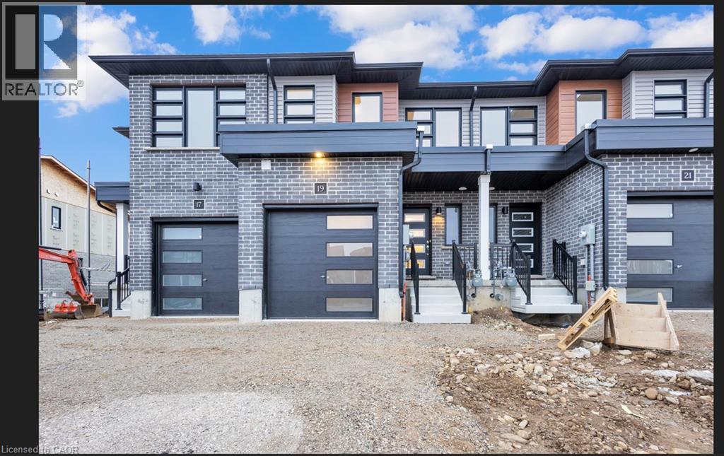 A modern two-story residential building with a gated entrance and a construction vehicle in the foreground.