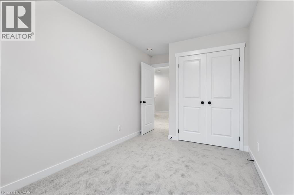 A white bedroom with a carpeted floor and a white door.