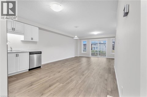 A spacious kitchen with white cabinets and a wooden floor.