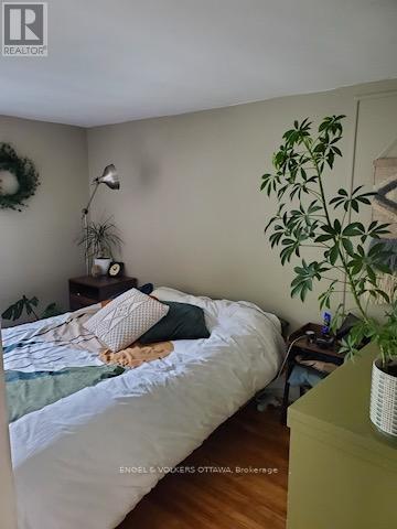 A bedroom with a bed, a plant, and a wreath on the wall.