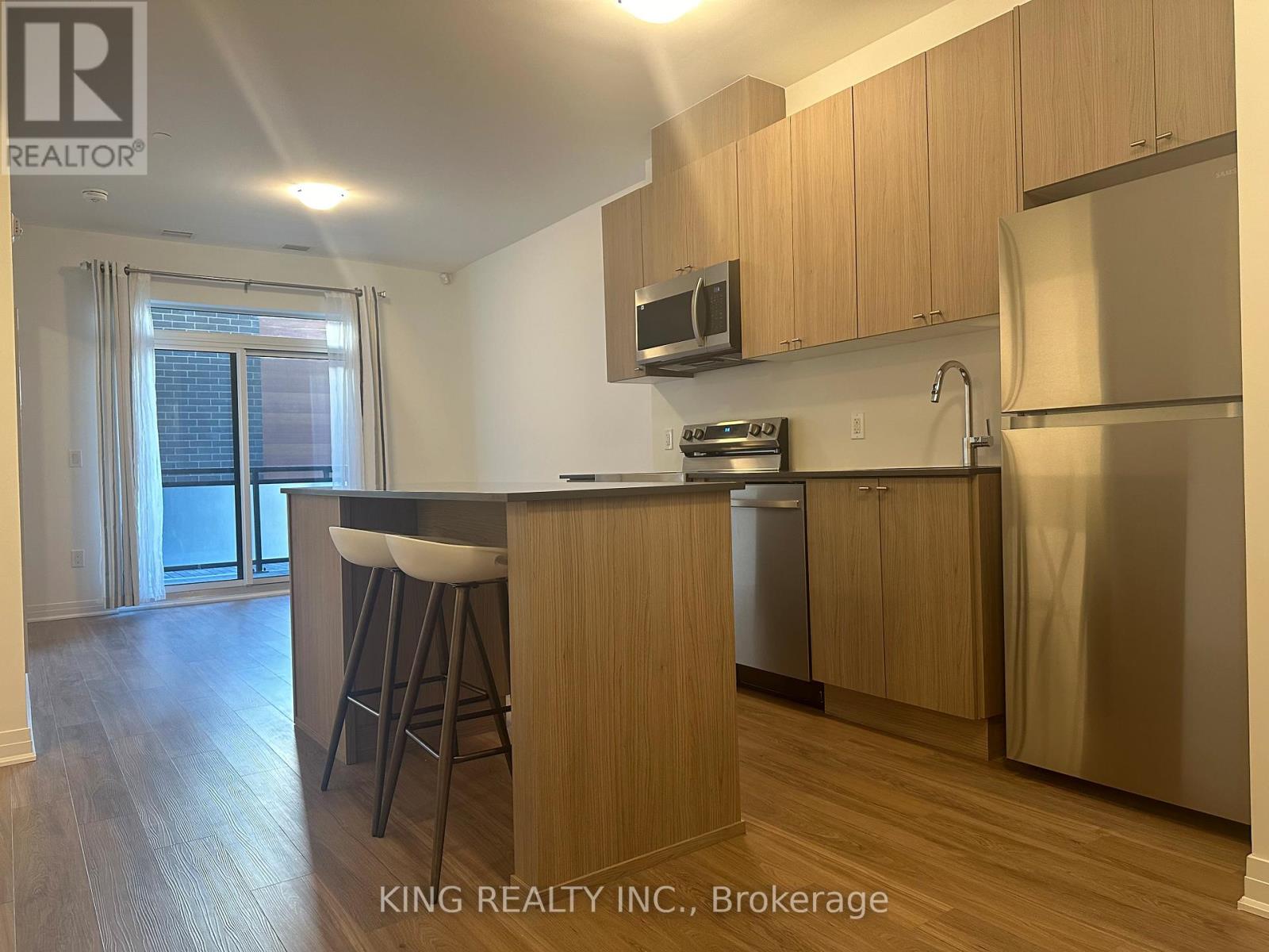 A kitchen with wooden cabinets and a stainless steel refrigerator.