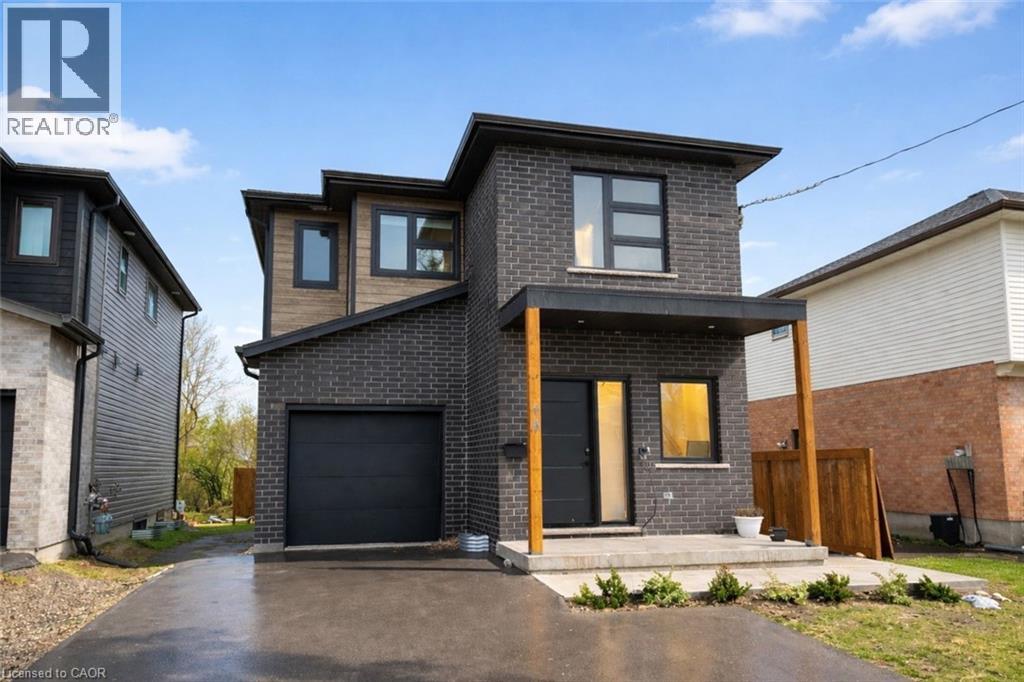 A modern house with a grey front yard and a black garage door.