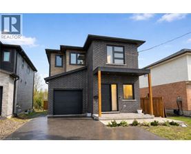 A modern house with a grey front yard and a black garage door.