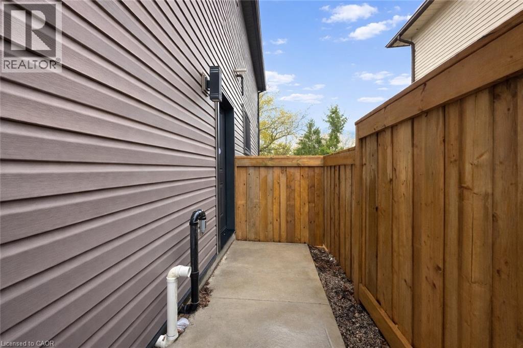 A wooden fence and a grey wall with a black gate.