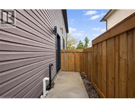 A wooden fence and a grey wall with a black gate.