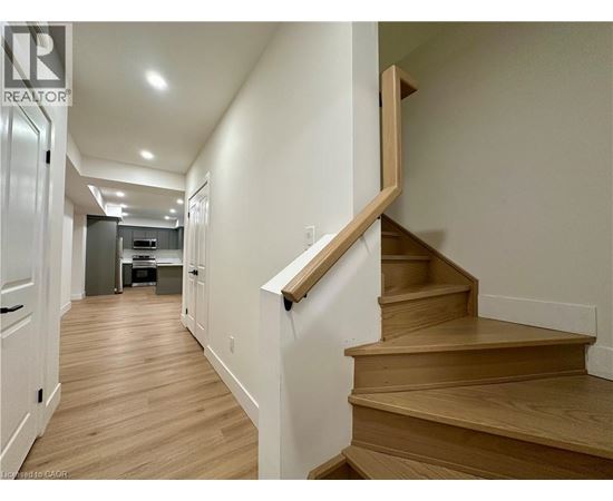A wooden staircase with a white wall on one side and a door on the other.