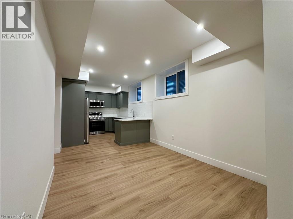 A spacious room with wooden flooring and a kitchen area.