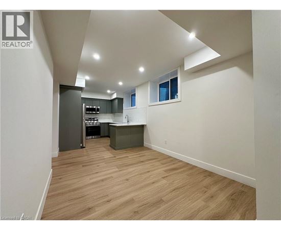 A spacious room with wooden flooring and a kitchen area.