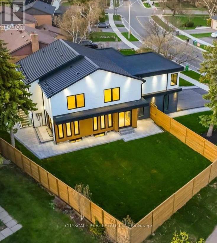 A modern house with a large front yard and a wooden fence.
