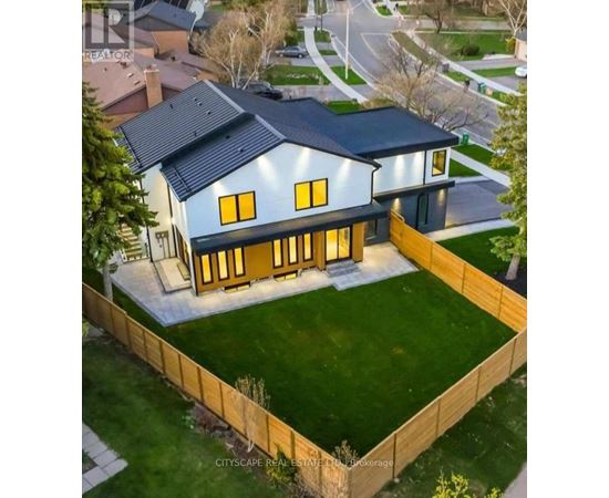 A modern house with a large front yard and a wooden fence.