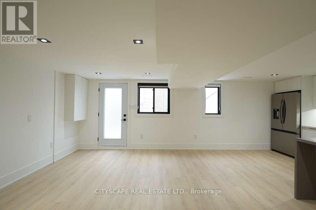 A spacious room with wooden flooring and white walls.