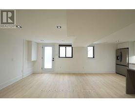 A spacious room with wooden flooring and white walls.
