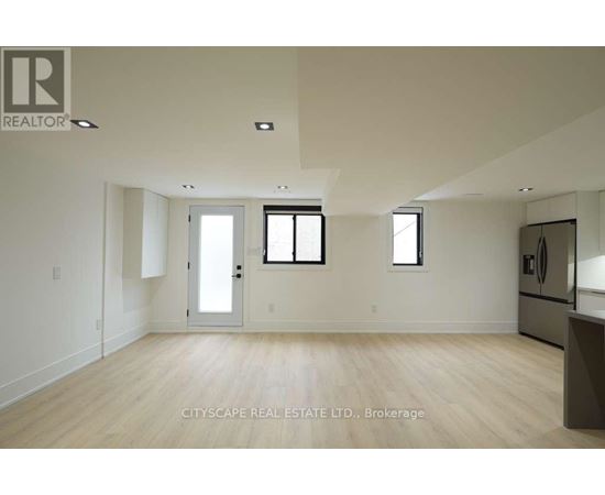 A spacious room with wooden flooring and white walls.
