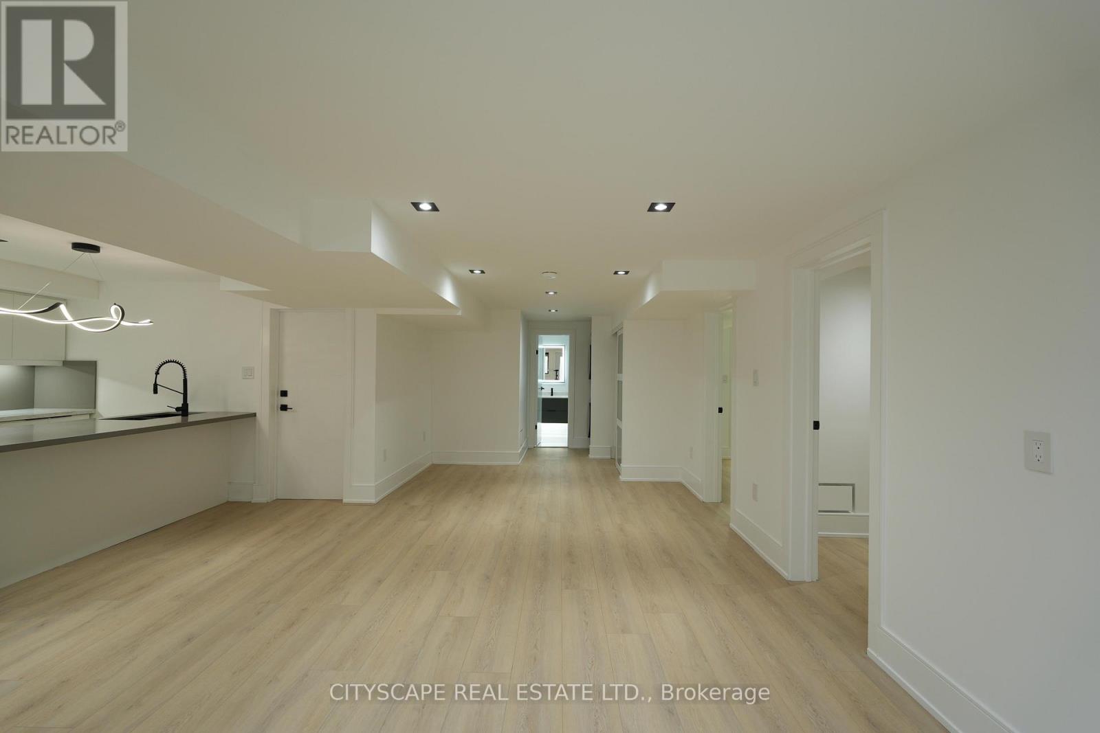 A spacious room with wooden floors and white walls, with a brokerage sign for CITYSCAPE REAL ESTATE LTD.