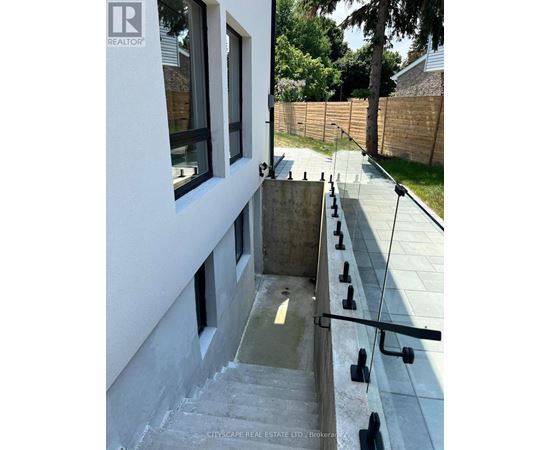 A concrete staircase with a glass railing leads down to a small pool.