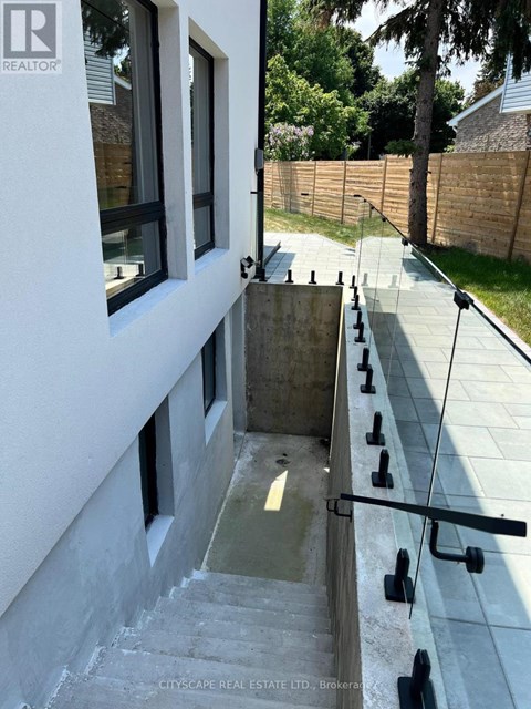 A concrete staircase with a glass railing leads down to a small pool.