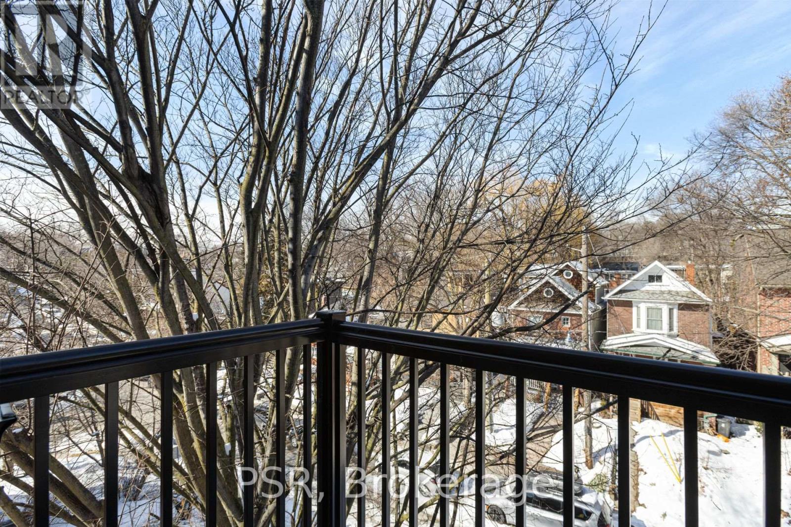 A view from a balcony looking out at a house and leafless trees.