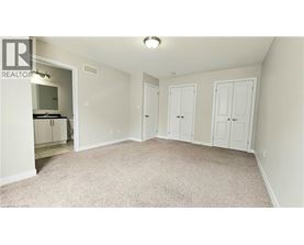 A bedroom with a white wardrobe and a carpeted floor.