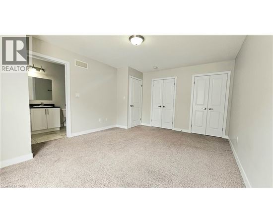 A bedroom with a white wardrobe and a carpeted floor.