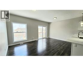 A spacious room with wooden flooring and a large window.