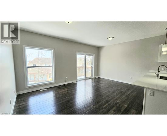 A spacious room with wooden flooring and a large window.