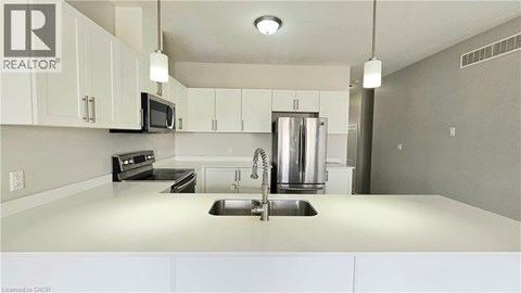 A kitchen with white cabinets and a stainless steel refrigerator.
