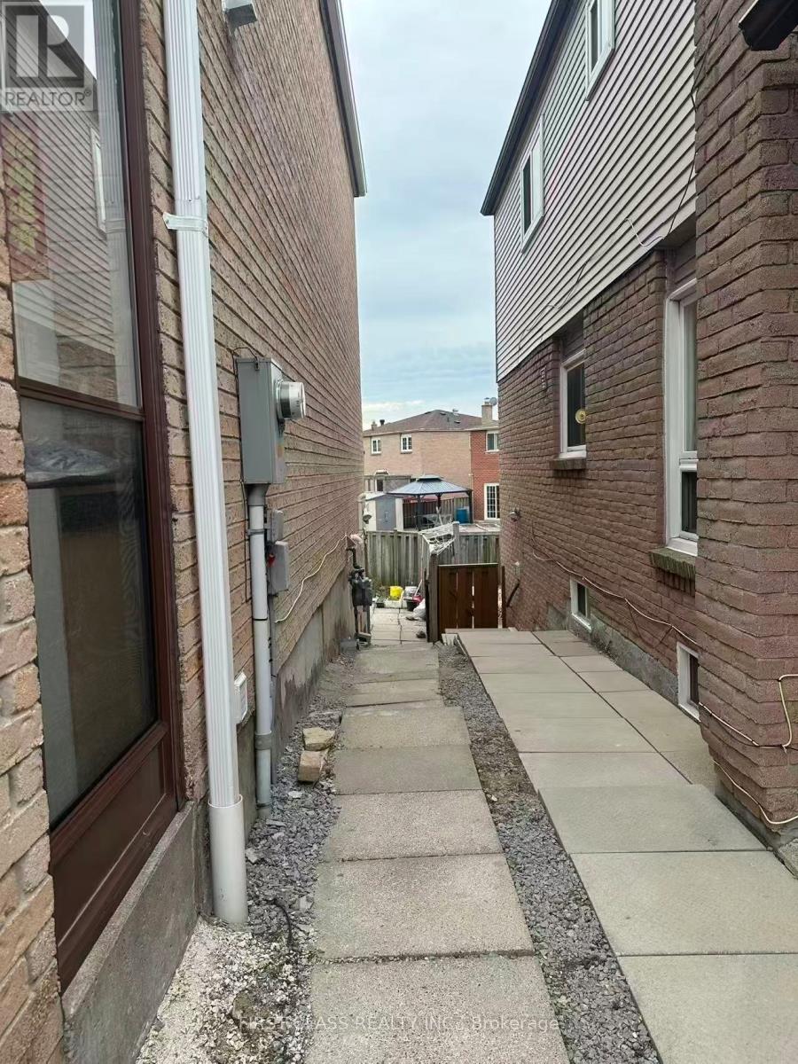 A narrow alleyway between two brick buildings with a Realty sign on the top left.