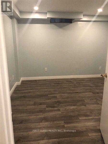 A room with wooden flooring and a white wall.
