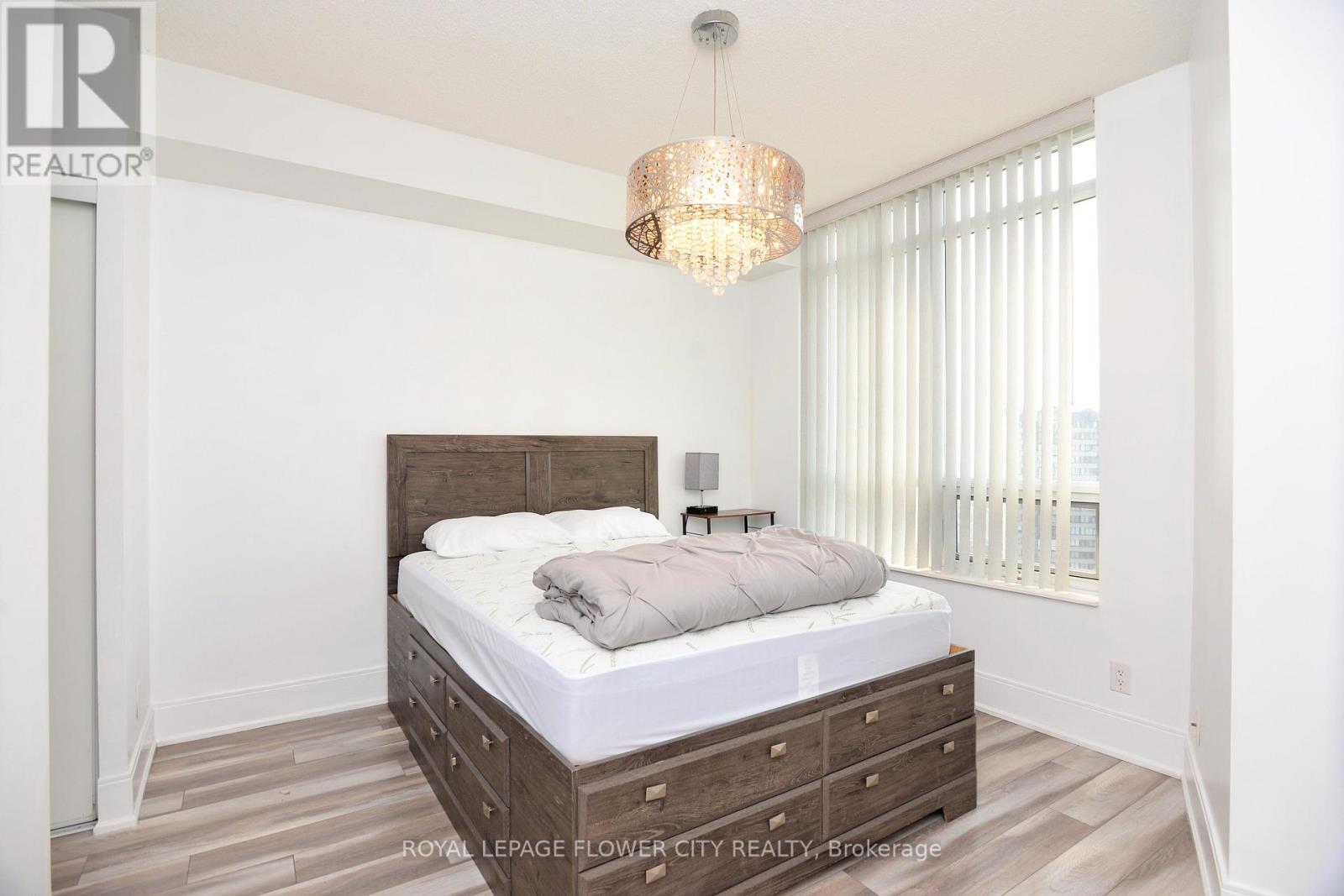 A bedroom with a large bed and a chandelier.