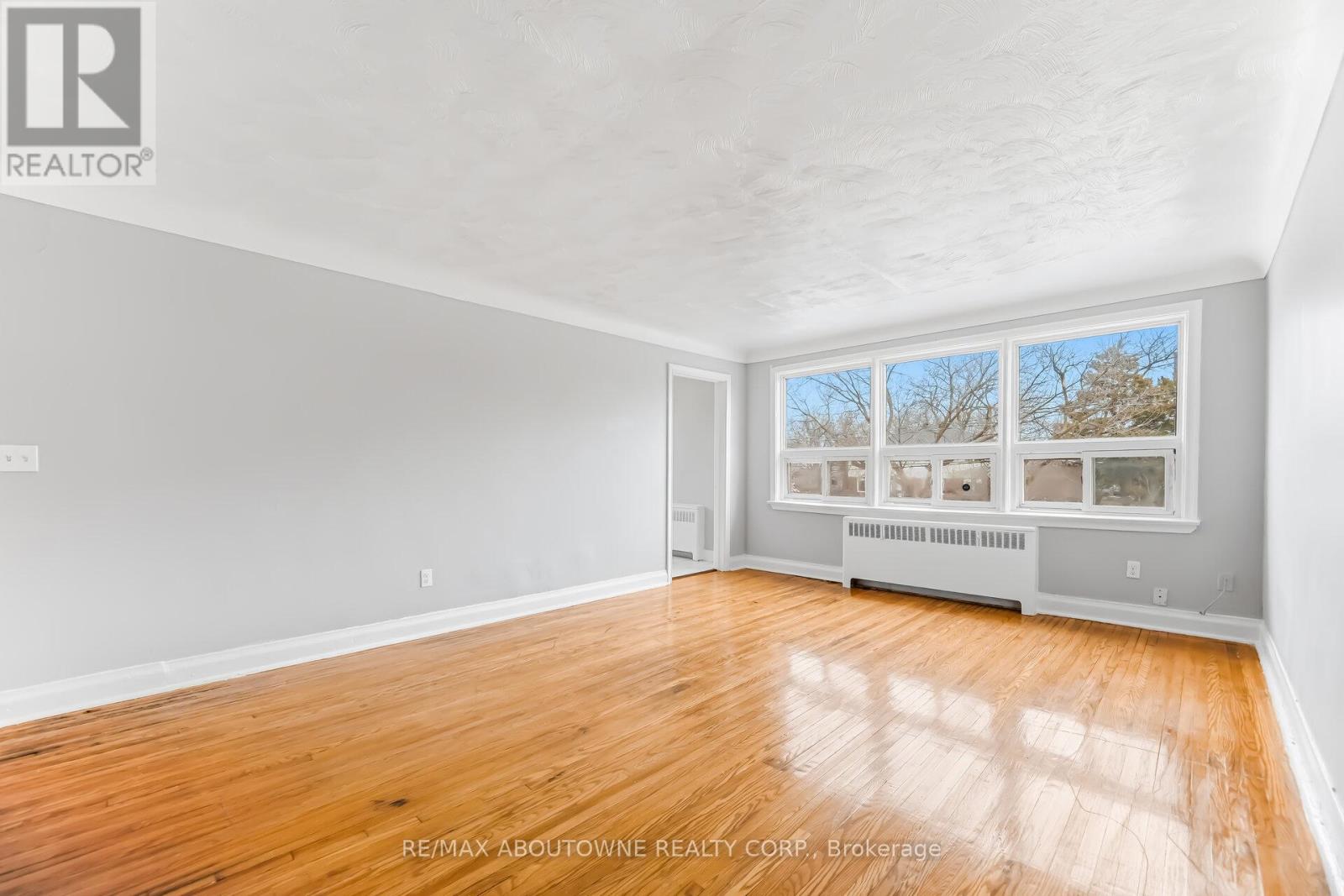 A spacious room with wooden flooring and a large window.