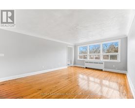 A spacious room with wooden flooring and a large window.