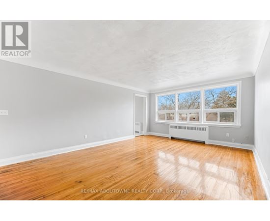 A spacious room with wooden flooring and a large window.