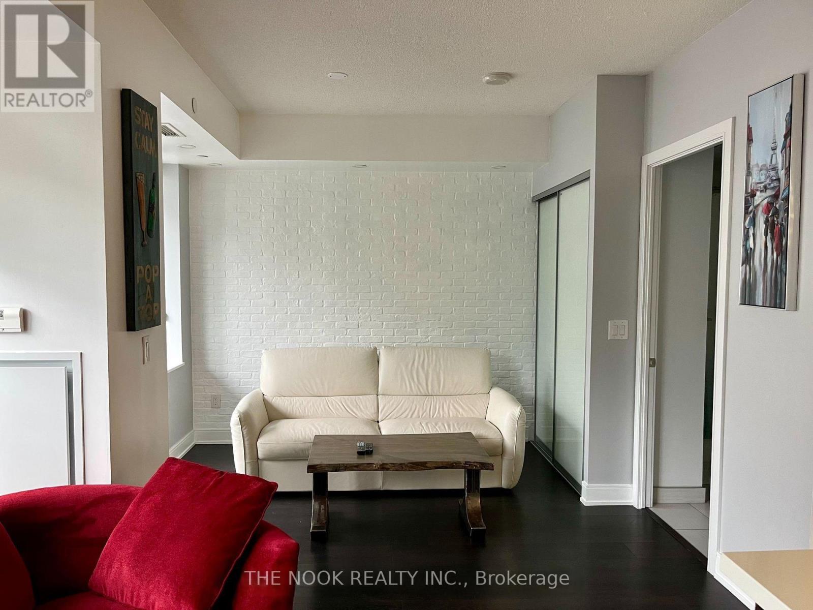 A living room with a white couch and a red pillow.