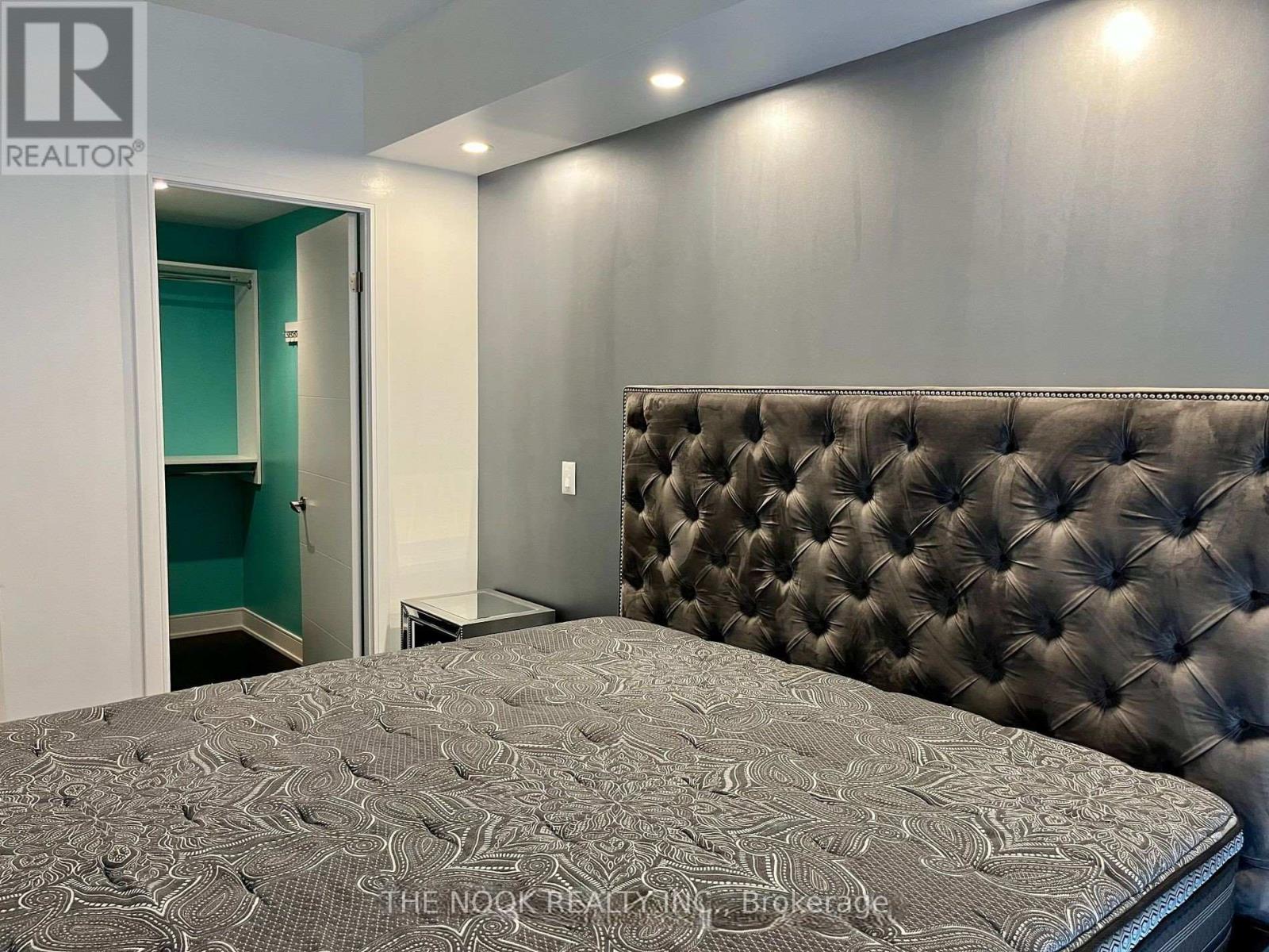 A bedroom with a tufted headboard and a patterned bedspread.
