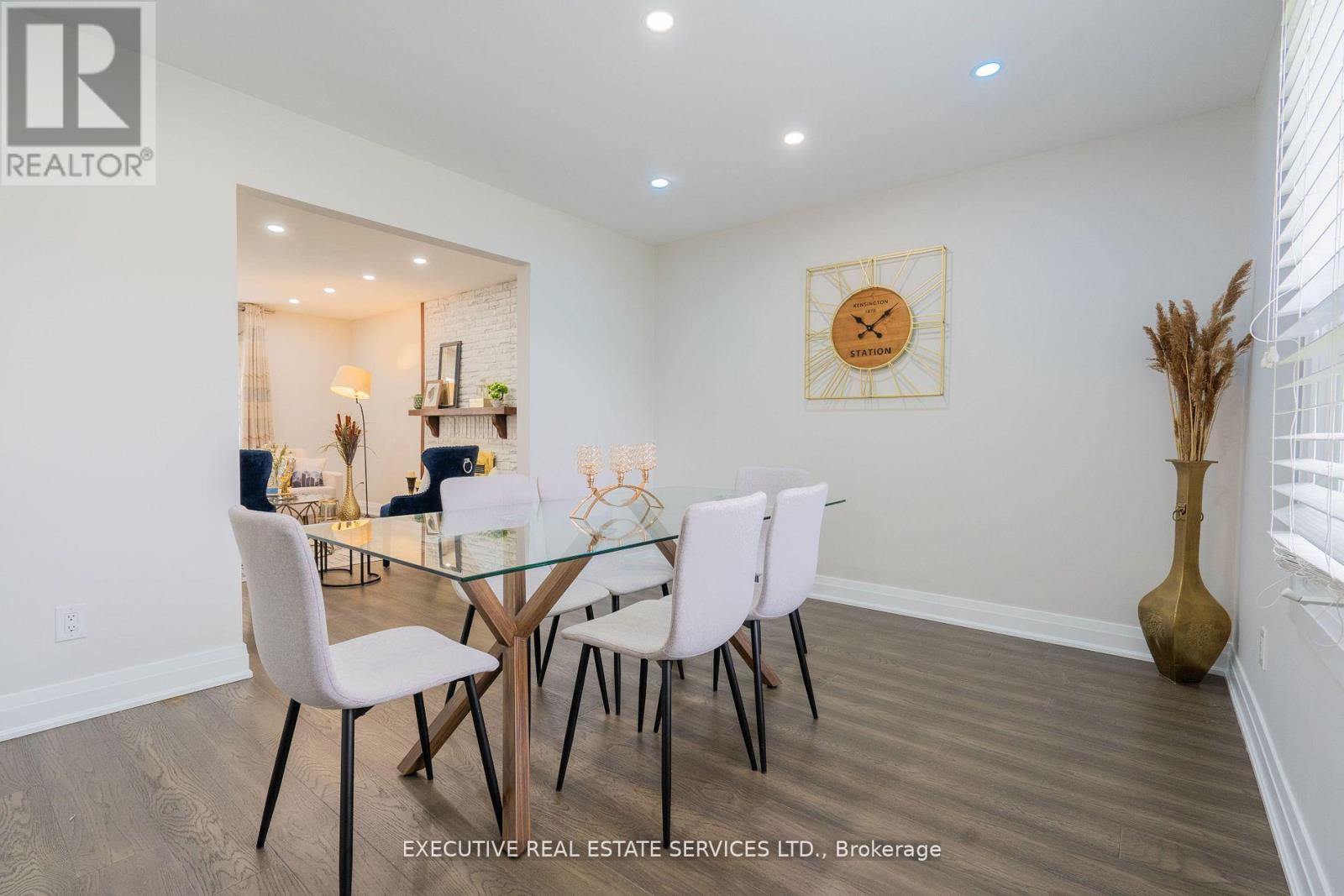 A dining room with a glass table and white chairs.