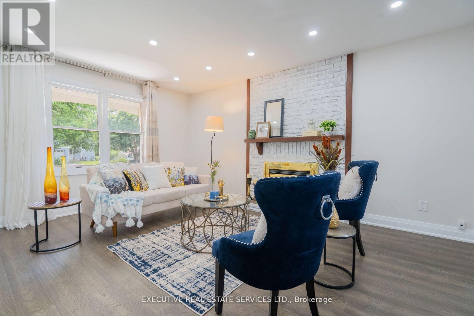 A living room with a white couch, a blue chair, and a small table with a vase on it.