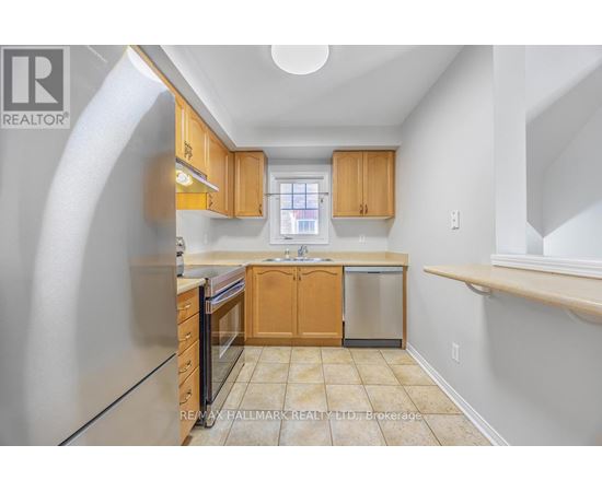 A kitchen with wooden cabinets and a stainless steel refrigerator.