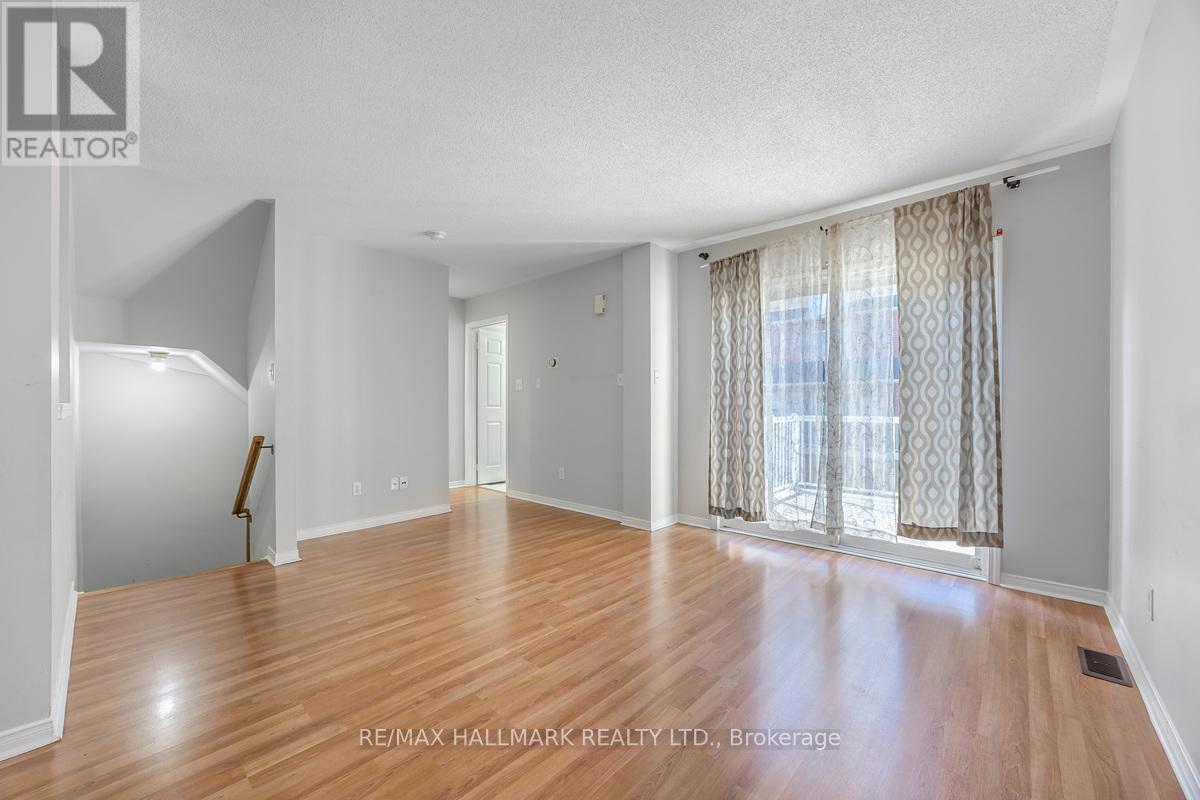 A spacious room with wooden flooring and a large window with curtains.