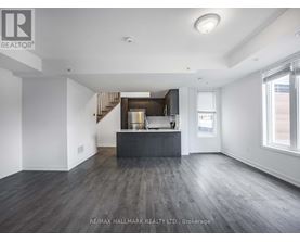A spacious room with wooden floors and a staircase leading to the upper level.