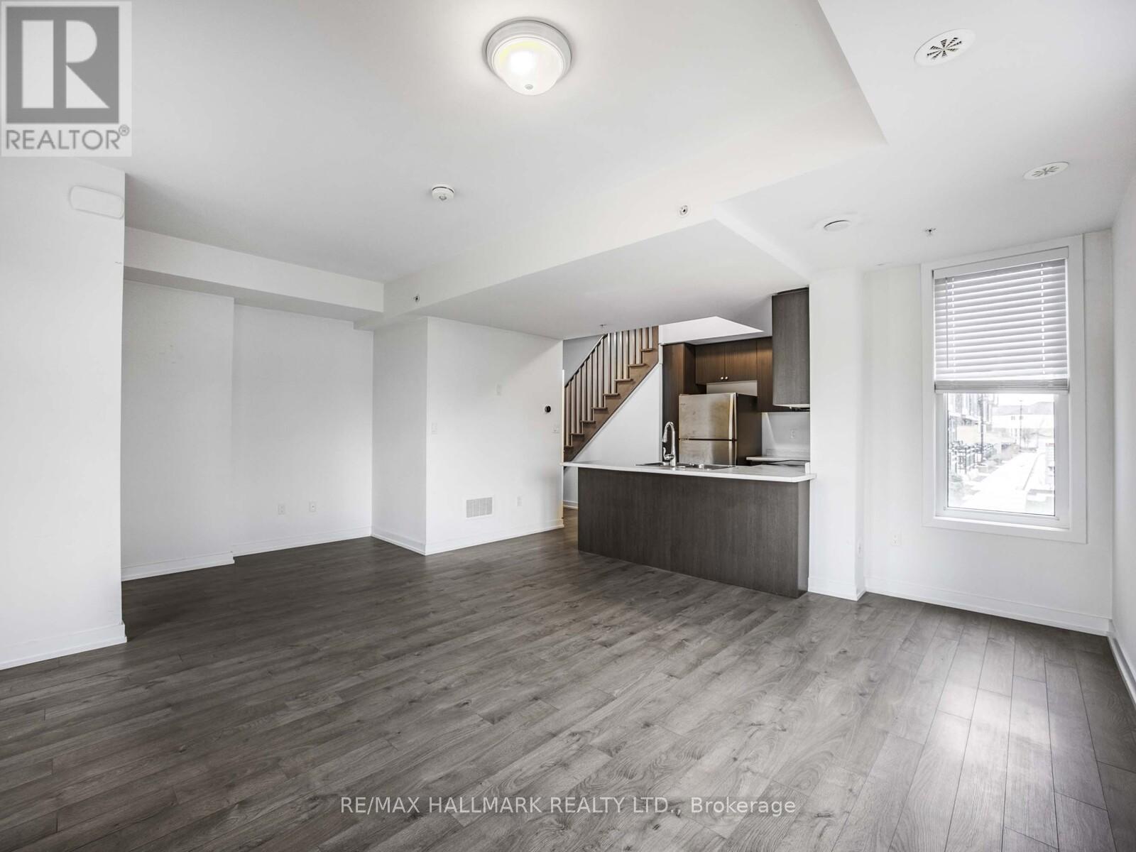 A spacious room with wooden flooring and a staircase leading to another level.