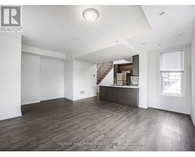 A spacious room with wooden flooring and a staircase leading to another level.
