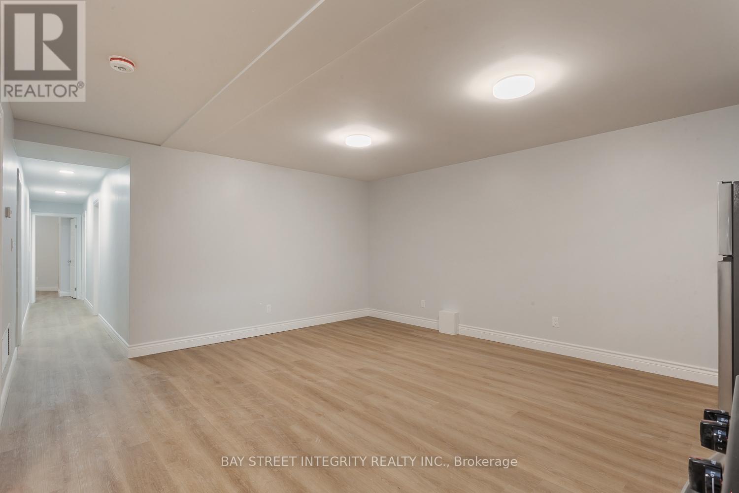 A spacious room with wooden flooring and white walls, likely a property for sale or rent.
