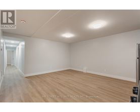 A spacious room with wooden flooring and white walls, likely a property for sale or rent.