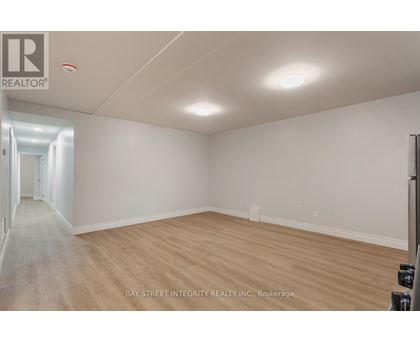 A spacious room with wooden flooring and white walls, likely a property for sale or rent.