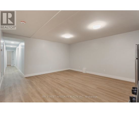 A spacious room with wooden flooring and white walls, likely a property for sale or rent.