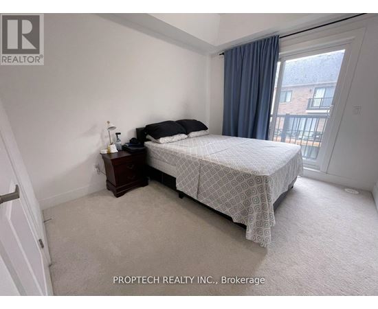 A bedroom with a bed, nightstand, and window.