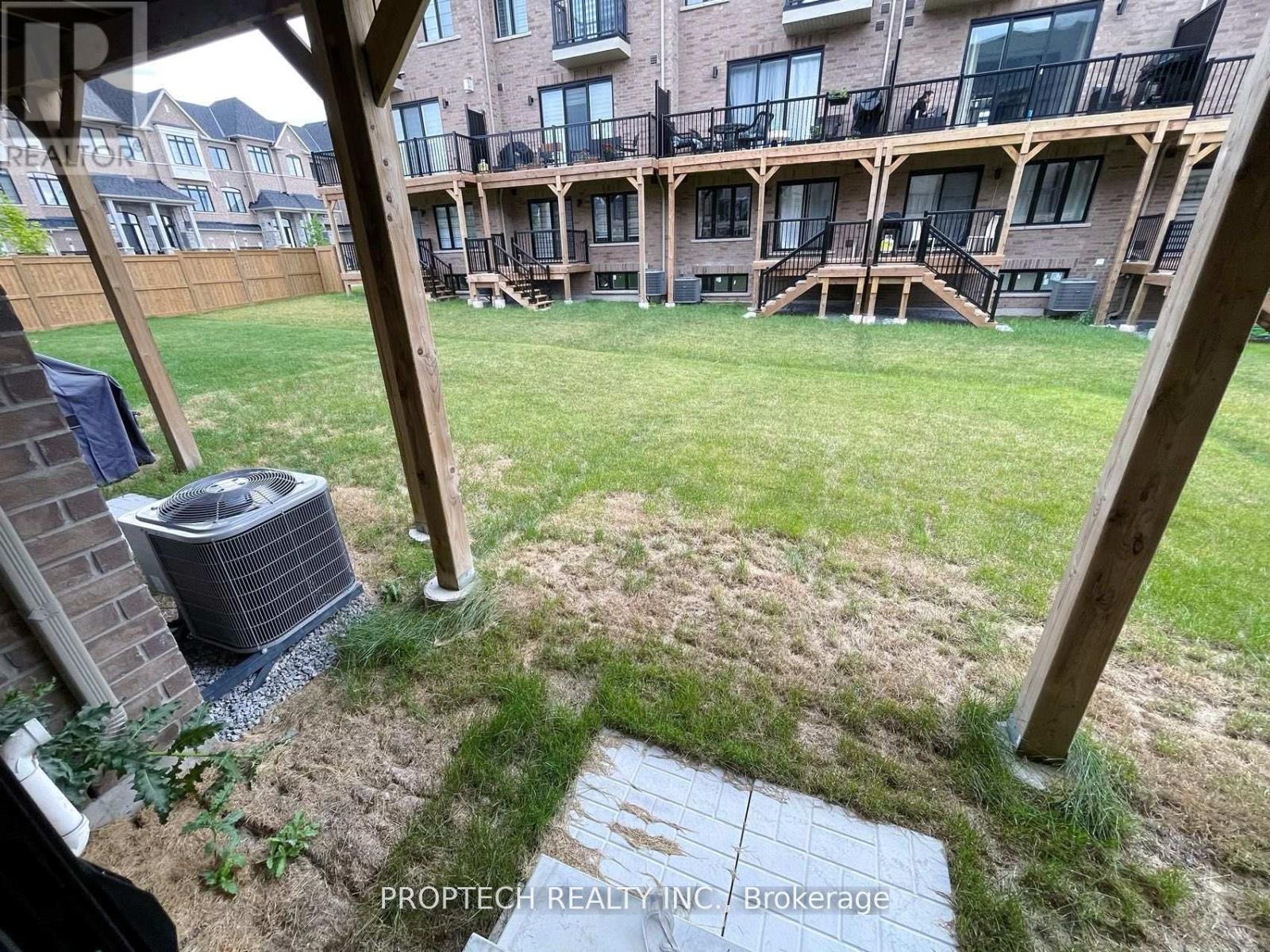 A patio area with a grassy lawn and a brick building in the background.