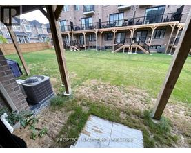 A patio area with a grassy lawn and a brick building in the background.