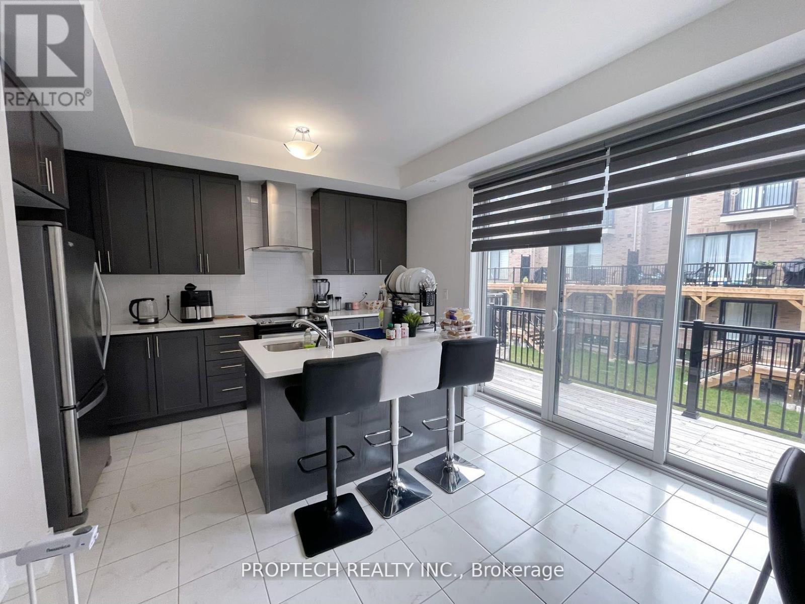 A kitchen with a refrigerator, sink, and a dining table with chairs.